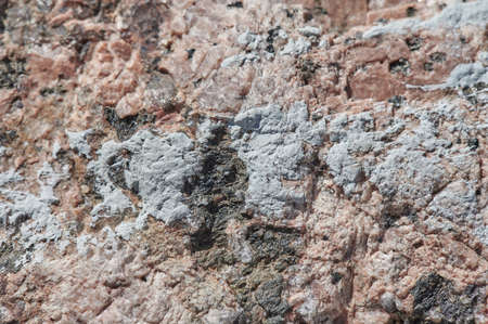 The surface of the chipped granite stone, rough, unpolished with multicolored splashes, natural, not treated, as a background for design work. Slightly discolored, horizontal, selective sharpnessの写真素材