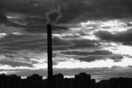 Silhouette of multi-storey buildings and heating pipes against the background of a dark cloudy sky late in the evening, in the last minutes of sunsetのeditorial素材