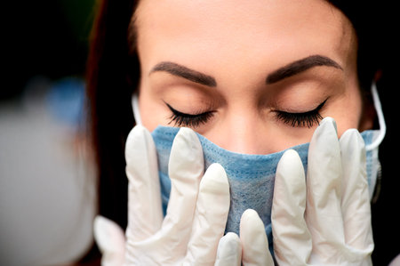 45-50-year-old brunette woman wearing a surgical protective mask to prevent coronavirus-causing...