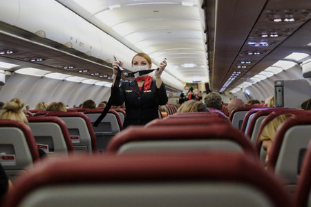 Saint Petersburg, Russia - November 13, 2020: A stewardess in a mask demonstrates to aircraft passengers the rules of conduct in an abnormal emergency and instructs on safety during the flightのeditorial素材