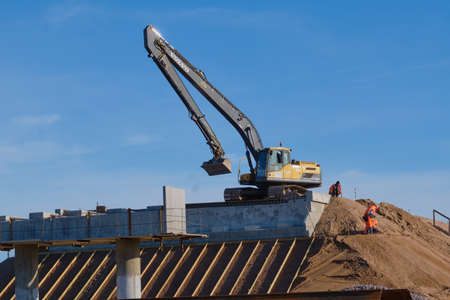 Leningrad region, Russia - September 20, 2020: the construction process of the international highway Scandinavia. Road, construction machinery, workers, cars, excavator, tractor, bridgeのeditorial素材