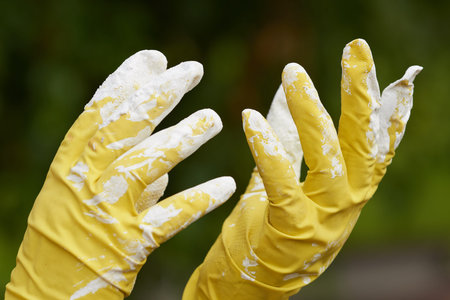 Painter's hands in rubber gloves soiled in white paint close-up.