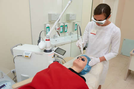 SAINT PETERSBURG-RUSSIA - JULY 24, 2017: The beautician conducts a procedure for laser rejuvenation of the facial skin of a young beautiful girl, the process of workのeditorial素材