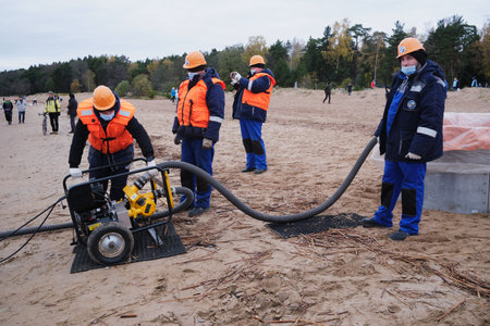 St. Petersburg, Russia - October 24, 2020: Employees of the environmental service clean up after low tide on the coast Gulf of Finland remove garbage, oil spills, harmful substances in mechanized wayのeditorial素材