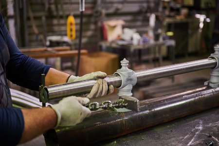 Metal pipe in the hands of a worker in the workshop for the manufacture of lamp posts. Product assembly processの写真素材
