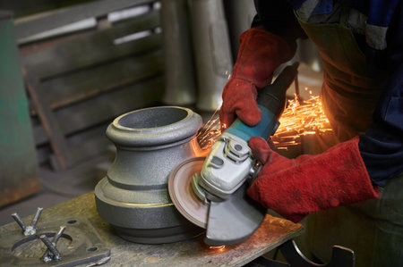 unrecognizable worker in red tarpaulin protective gloves cleans the chamfers of the part using a...