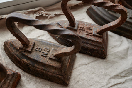 conceptual photography - a set of antique cast iron irons on the surface of a canvas lying on a windowsill symbolizing group relationshipsの写真素材