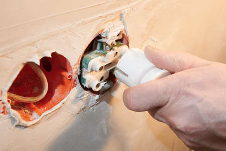 Dangerous connection of an electrical plug to a new socket without a decorative cover installedの写真素材
