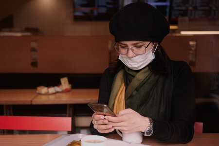 a girl of 25 years old in glasses and a dark beret in a medical mask to protect against coronavirus infection Covid-19の写真素材
