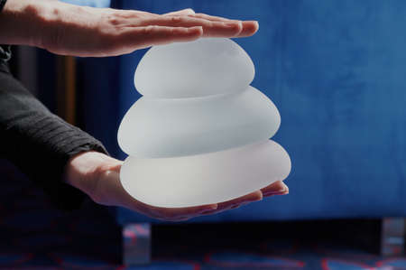 Silicone female breast implant is the main object of plastic surgery in human hands. Demonstration of the qualities of a medical objectの写真素材