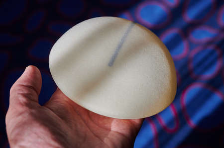 Silicone female breast implant is the main object of plastic surgery in human hands. Demonstration of the qualities of a medical objectの写真素材
