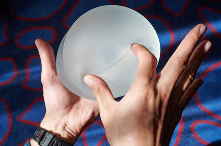 Silicone female breast implant is the main object of plastic surgery in human hands. Demonstration of the qualities of a medical objectの写真素材