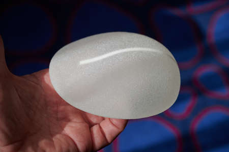 Silicone female breast implant is the main object of plastic surgery in human hands. Demonstration of the qualities of a medical objectの写真素材