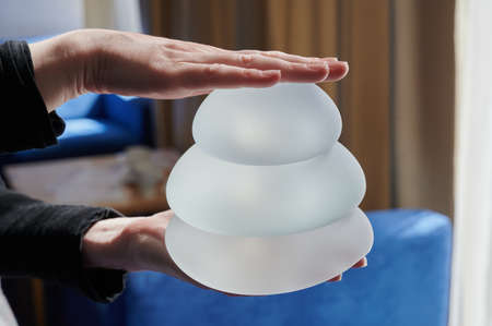 Silicone female breast implant is the main object of plastic surgery in human hands. Demonstration of the qualities of a medical objectの写真素材