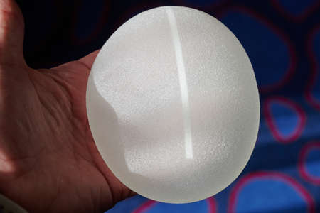 Silicone female breast implant is the main object of plastic surgery in human hands. Demonstration of the qualities of a medical objectの写真素材