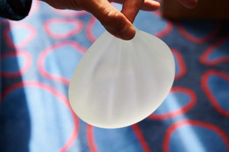 Silicone female breast implant is the main object of plastic surgery in human hands. Demonstration of the qualities of a medical objectの写真素材
