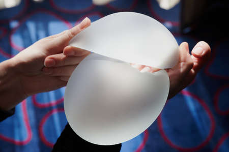 Silicone female breast implant is the main object of plastic surgery in human hands. Demonstration of the qualities of a medical objectの写真素材