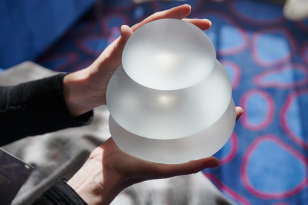 Silicone female breast implant is the main object of plastic surgery in human hands. Demonstration of the qualities of a medical objectの写真素材