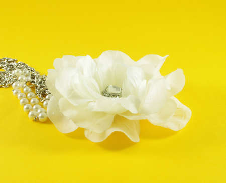 Closeup of fabric flower with pearls over yellow backgroundの写真素材