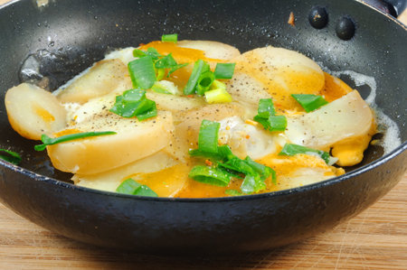 fried eggs with potato on panの写真素材