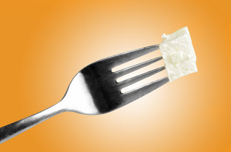 old used fork with piece of cheeseの写真素材