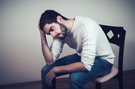 sad handsome man with beard sitting on chair