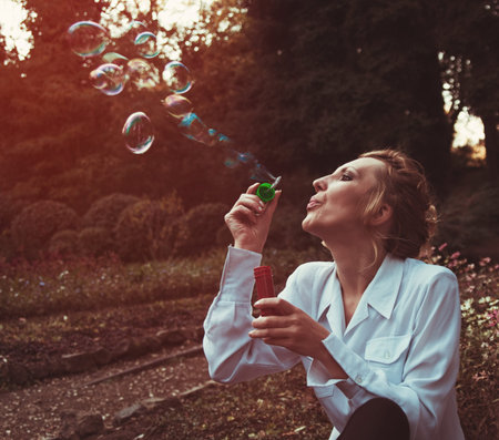 woman in the autumn park blowing bubbles