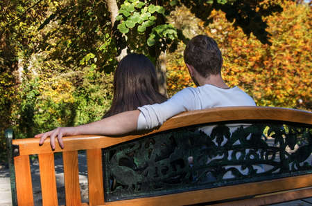 young couple in autumn park sitting on benchの写真素材