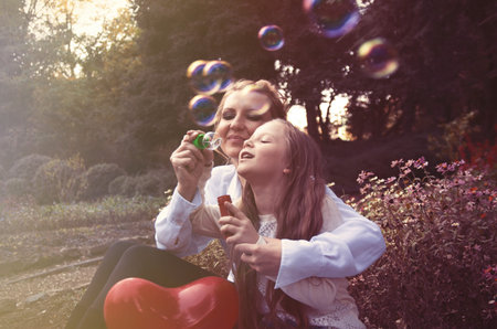 mother and daughter in the autumn park blowing bubbles
