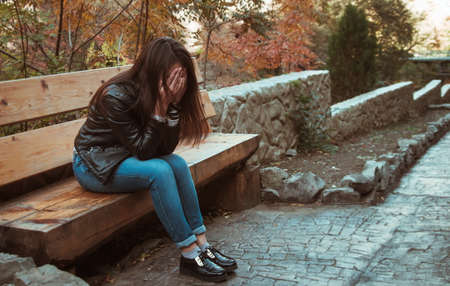 depressed girl sitting on bench in the parkの写真素材