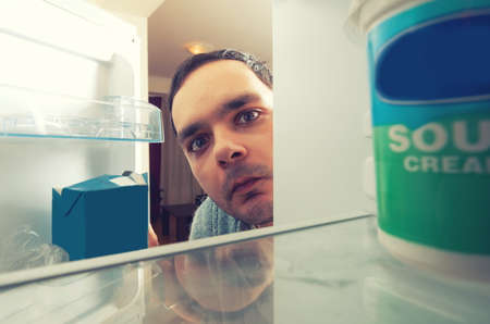 hungry man with funny face opens the fridgeの写真素材