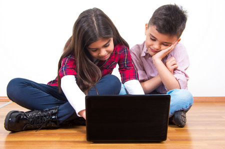 happy brother and sister using the laptopの写真素材