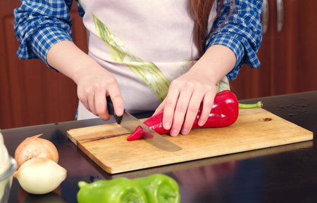 Little girl is cutting vegetables for salad closeupの写真素材
