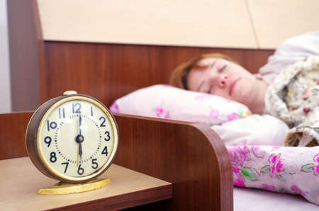 woman and alarm clock in the bedroomの写真素材