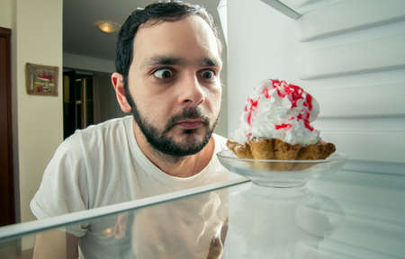 funny man sees the sweet cake in the fridgeの写真素材