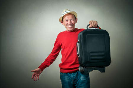 portrait of the funny senior man with travel bagの写真素材
