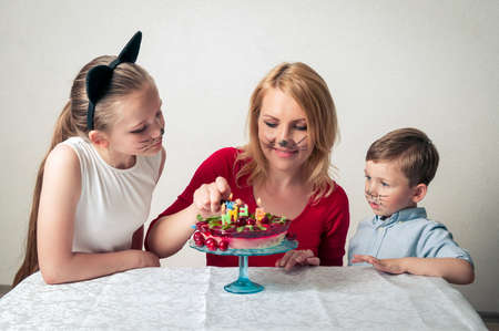 Little boy with mum and sister with birthday cakeの写真素材