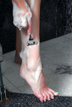 Woman shaving legs in the showerの写真素材