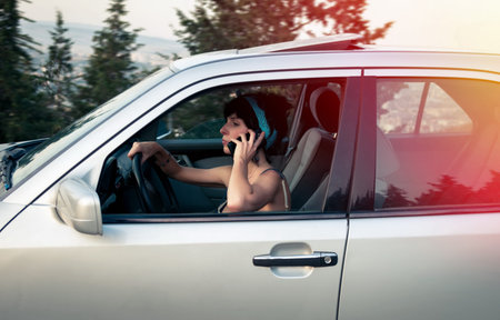 Pretty woman driving the car and talking on phoneの写真素材