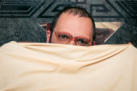 Funny man with glasses in the bed