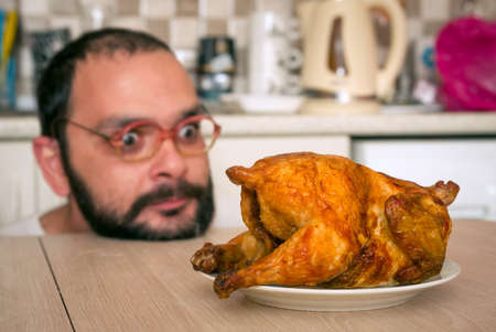 Funny hungry man looking on the chickenの写真素材