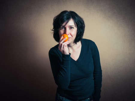 Brunette lady holding a tangerineの写真素材