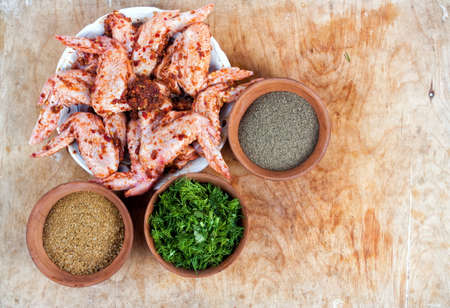 Spices in the bowls with chicken closeup on tableの写真素材