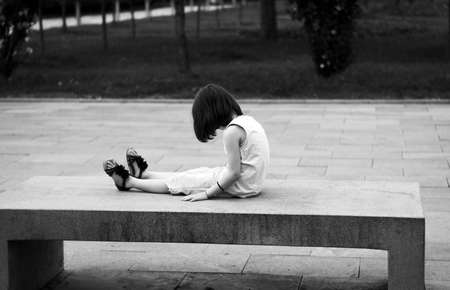 Little girl sitting alone on the benchの写真素材