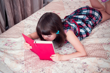 Little girl reading a book at homeの写真素材