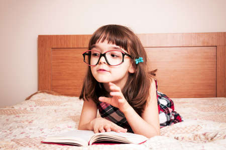 Little girl reading a book at homeの写真素材