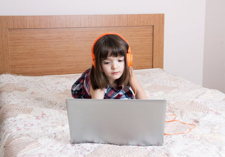 Little girl using the laptop with earphones