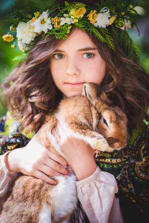 Little girl playing with white rabbit in summer day outdoorの写真素材