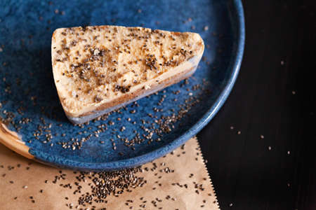 Cheesecake on a blue plate with scattered sesame seedsの写真素材