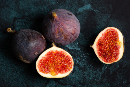 Ripe figs. Cut in half. Purple background. Top view.